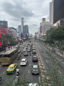 Busy Bangkok street with cars and motorcycles, showing chaotic traffic for pedestrians.