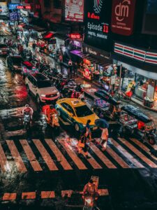 Flooded street in Bangkok during the rainy season, with puddles and traffic.